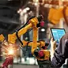 Das Bild zeigt einen Maschinenbediener mit Tablet-Computer vor mehreren Schweißrobotern