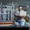 Ingenieur mit Laptop vor einer Maschine