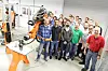 Studierende hinter Roboterarm,