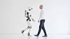 Human-Robot Interaction: A man and a humanoid robot walk side-by-side, provoking questions about the future of artificial intelligence and the relationship between humans and technology.