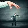 Mann als Marionette an großer Hand,
