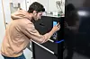 Brandon Alves drückt auf ein Touchscreen an dem geschlossenen, schwarz lackierten 3D-Drucker.