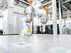 Ein Kuka Roboterarm steht bereit auf einem Arbeitstisch.