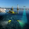 Das Bild zeigt die vier Komponenten von SeaClear: Ein autonomes Boot, eine Drohne und zwei Unterwasserroboter.
