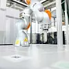 Ein Kuka Roboterarm steht bereit auf einem Arbeitstisch.