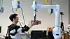 Forscher Federico Masiero nimmt ein Päckchen entgegen, dessen Gewicht der Roboter vorher bereits an das Exoskelett übermittelt hat.