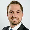 Nahaufnahme eines lächelnden Mannes im Anzug vor hellem Hintergrund. Eric Jung, Omron Marketing Specialist Vision