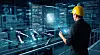 Engineer in yellow hard hat monitoring AI supply chain and predictive maintenance logs on holographic interface in smart factory, industrial automation concept.