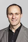 Porträt eines Mannes im grauen Sakko und schwarzen Hemd vor hellem Hintergrund. Dr.-Ing. Werner Kraus, Forschungsleiter beim Fraunhofer IPA