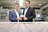 Die cellumation-Gründer Dr.-Ing. Hendrik Thamer (rechts) und Dr.-Ing. Claudio Uriarte mit einem Element der patentierten Celluveyor-Technologie. Nach der Übernahme durch Symbotic soll die softwaregesteuerte Sortiertechnik künftig auch in dessen Robotiksystemen zum Einsatz kommen.